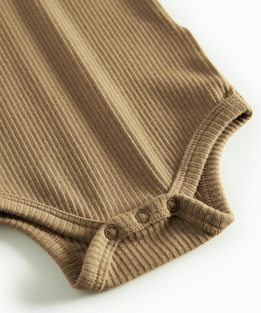 Brun ribstrikket babybody med lange ærmer, stolpe knaplukning og trykknapper mellem benene
