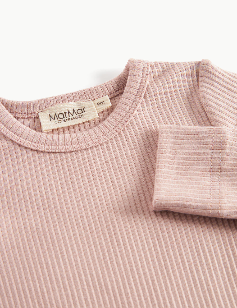 Nærbillede af ribstrikket materiale og hals på lyserød body til børn