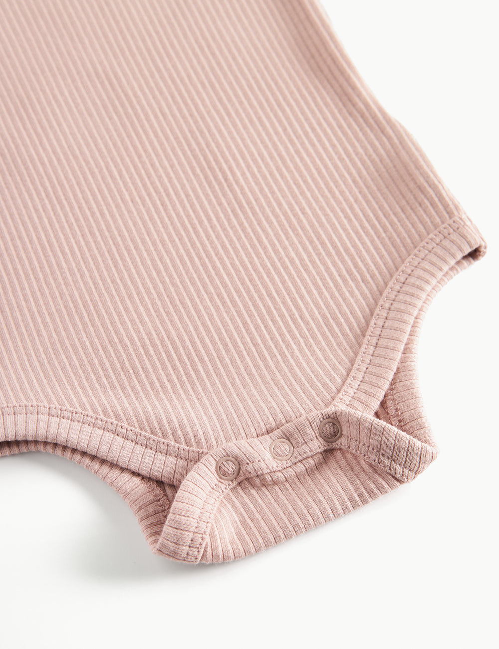 Detaljebillede af trykknapper ved benåbning på lyserød body til baby