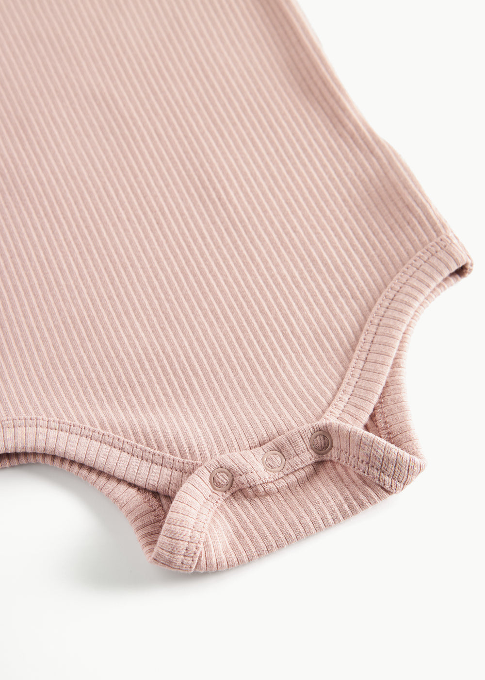 Detaljebillede af trykknapper ved benåbning på lyserød body til baby