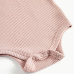 Detaljebillede af trykknapper ved benåbning på lyserød body til baby