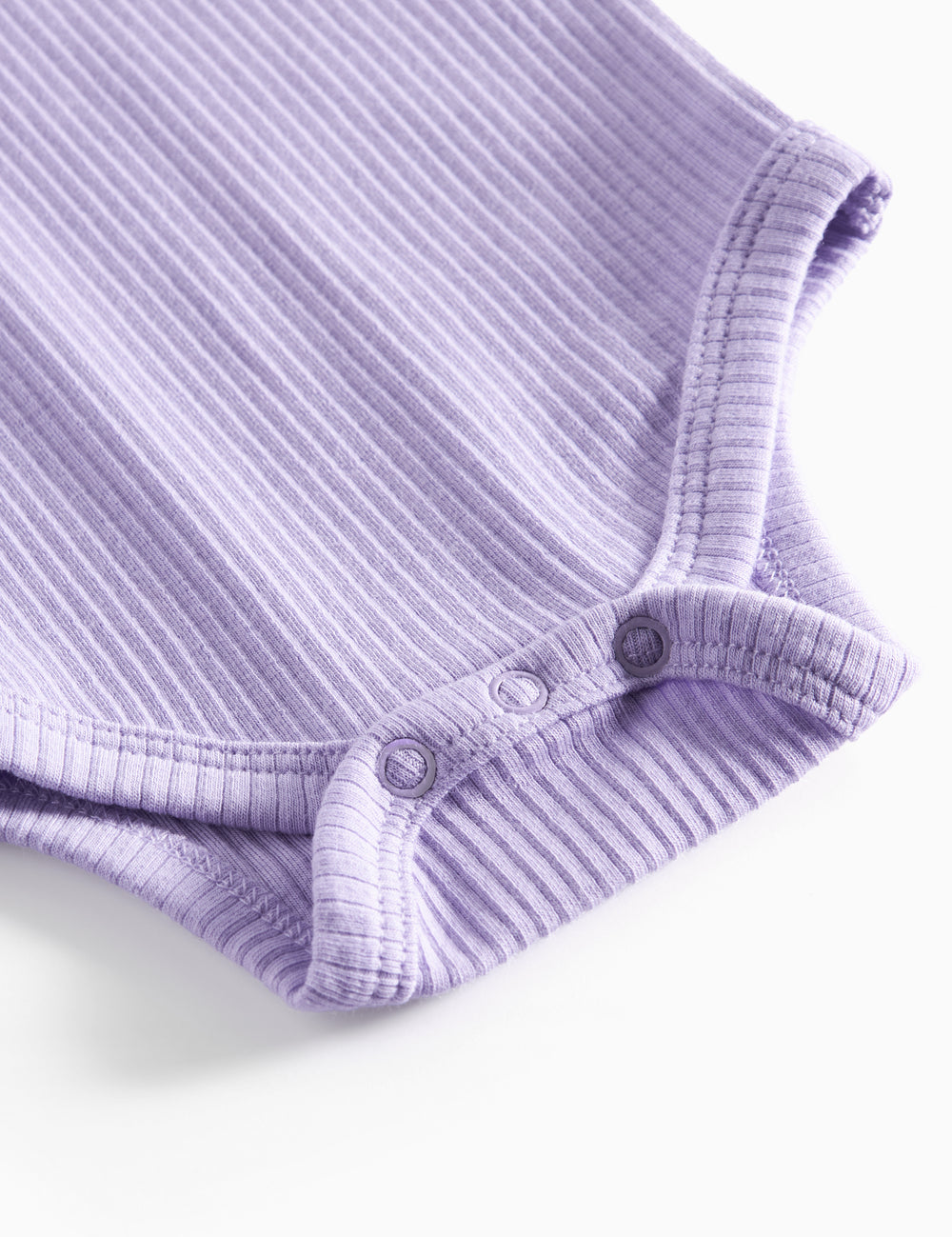 Lilla ribstrikket babybody med lange ærmer og knapper mellem benene