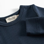 Blå ribstrikket babybody med lange ærmer og knapper mellem benene