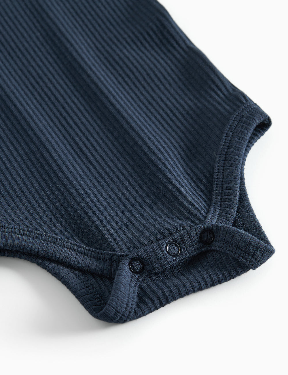 Blå ribstrikket babybody med lange ærmer og knapper mellem benene