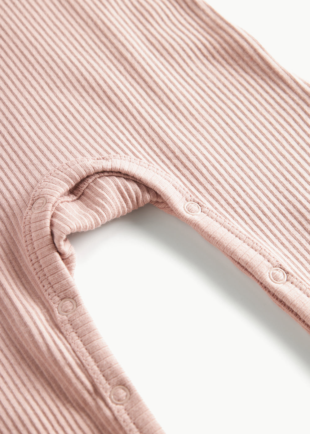 Ribbstrikket lyserød heldragt til baby i blødt materiale med lange ærmer, lange ben og knapper