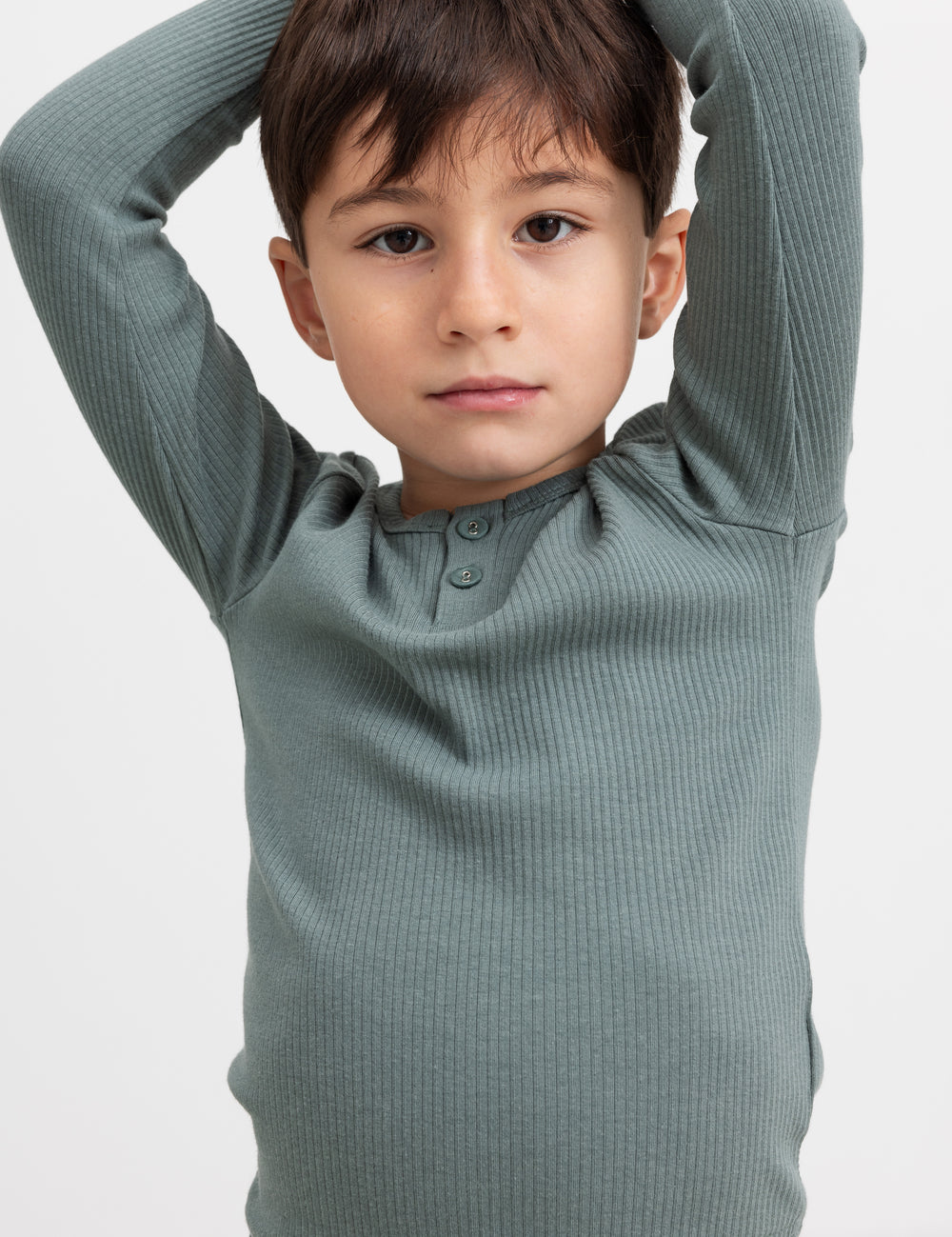 Dreng i grøn ribstrikket t-shirt løfter armene.