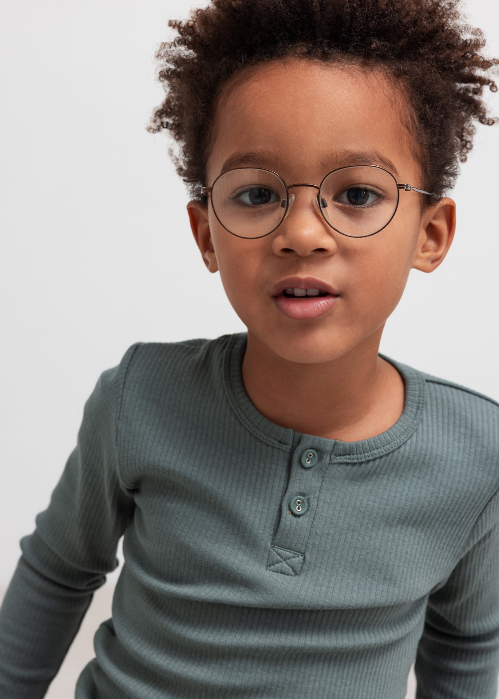 Dreng iført grøn ribbstikket t-shirt med knapper og briller