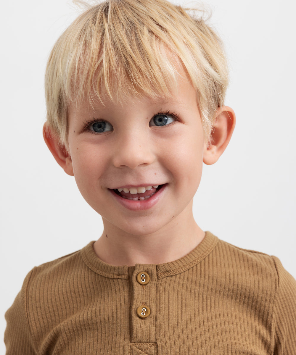 Glad dreng iført brun ribstrikket langærmet t-shirt