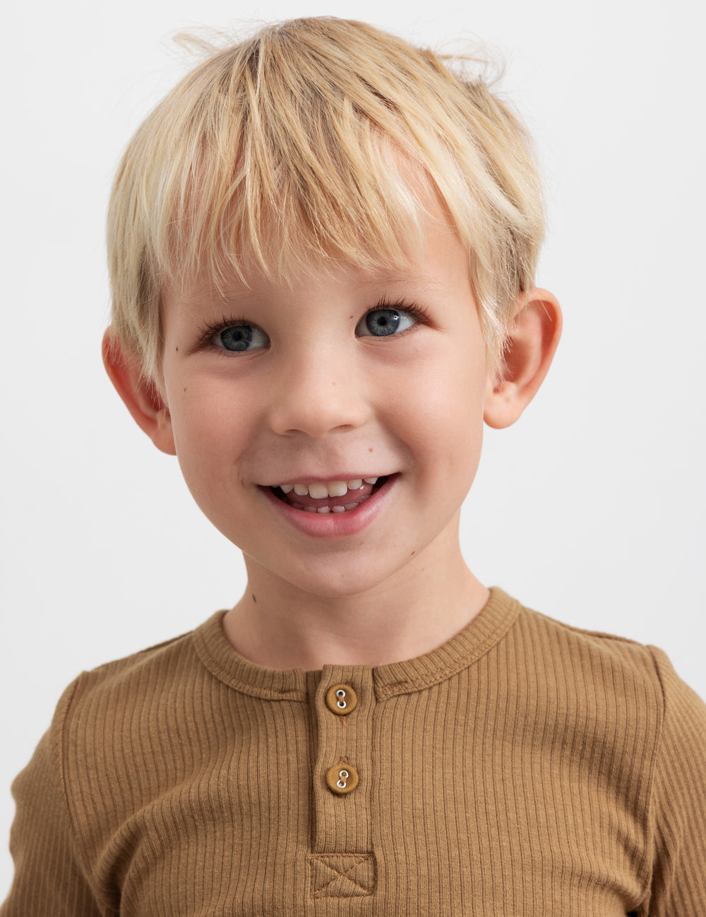 Glad dreng iført brun ribstrikket langærmet t-shirt