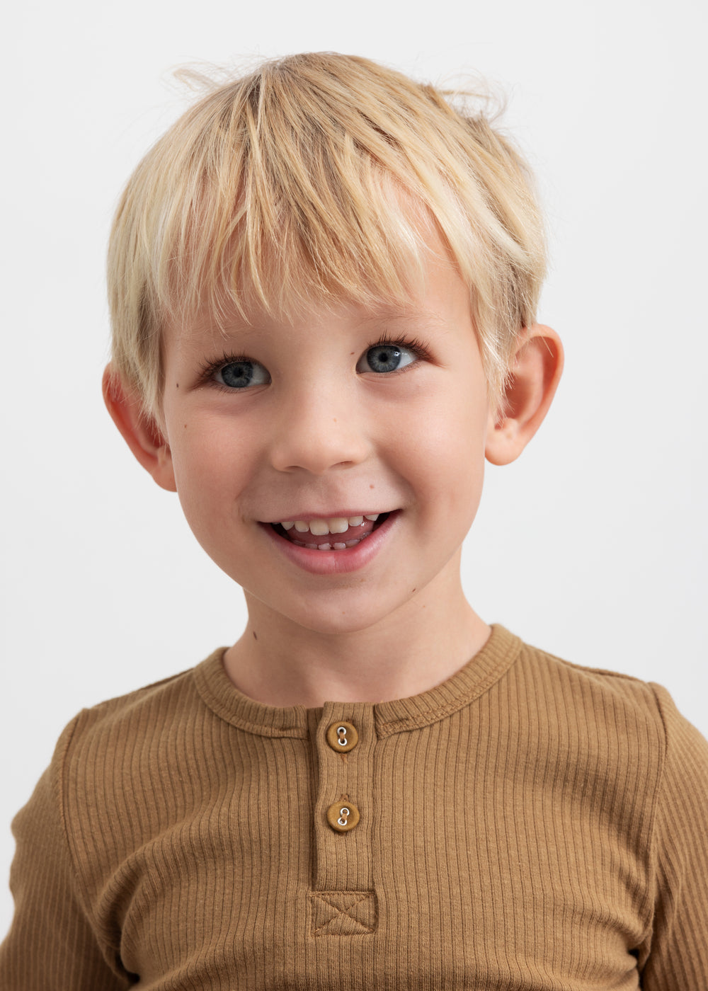 Glad dreng iført brun ribstrikket langærmet t-shirt