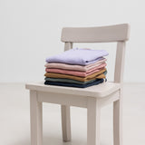 Stablet ribstrikket børnetøj i forskellige farver på en stol