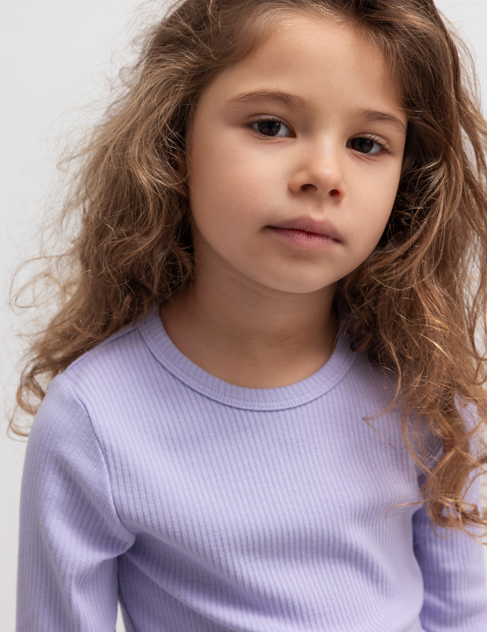 Stak af børne t-shirts i flere farver placeret på en stol