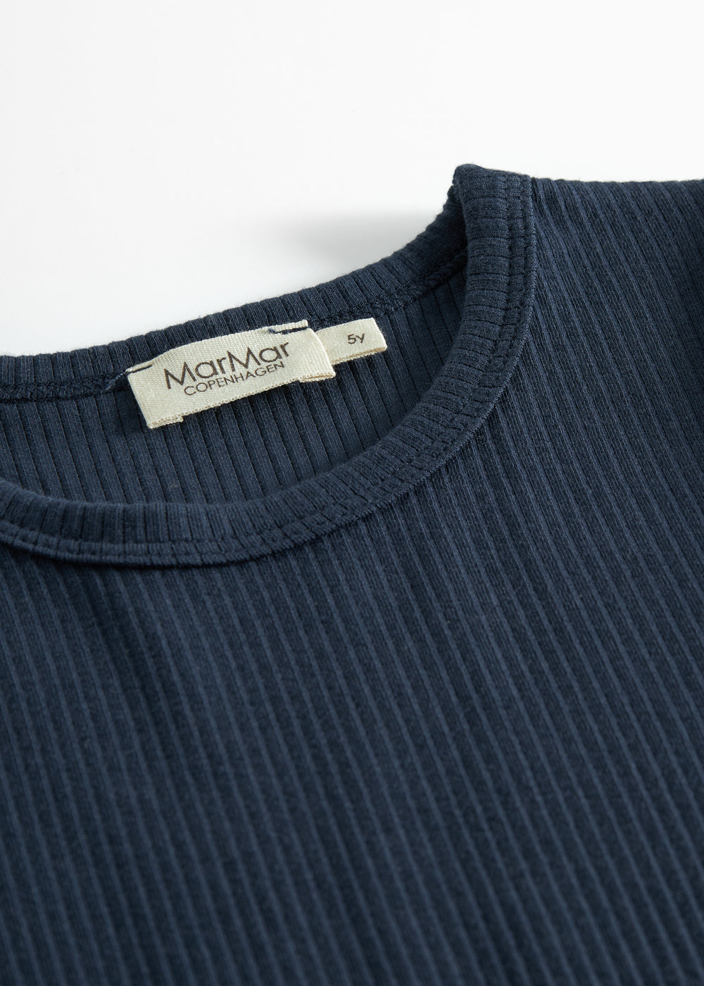 Nærbillede af ribstrikket stof og mærkat på navyblå børne t-shirt