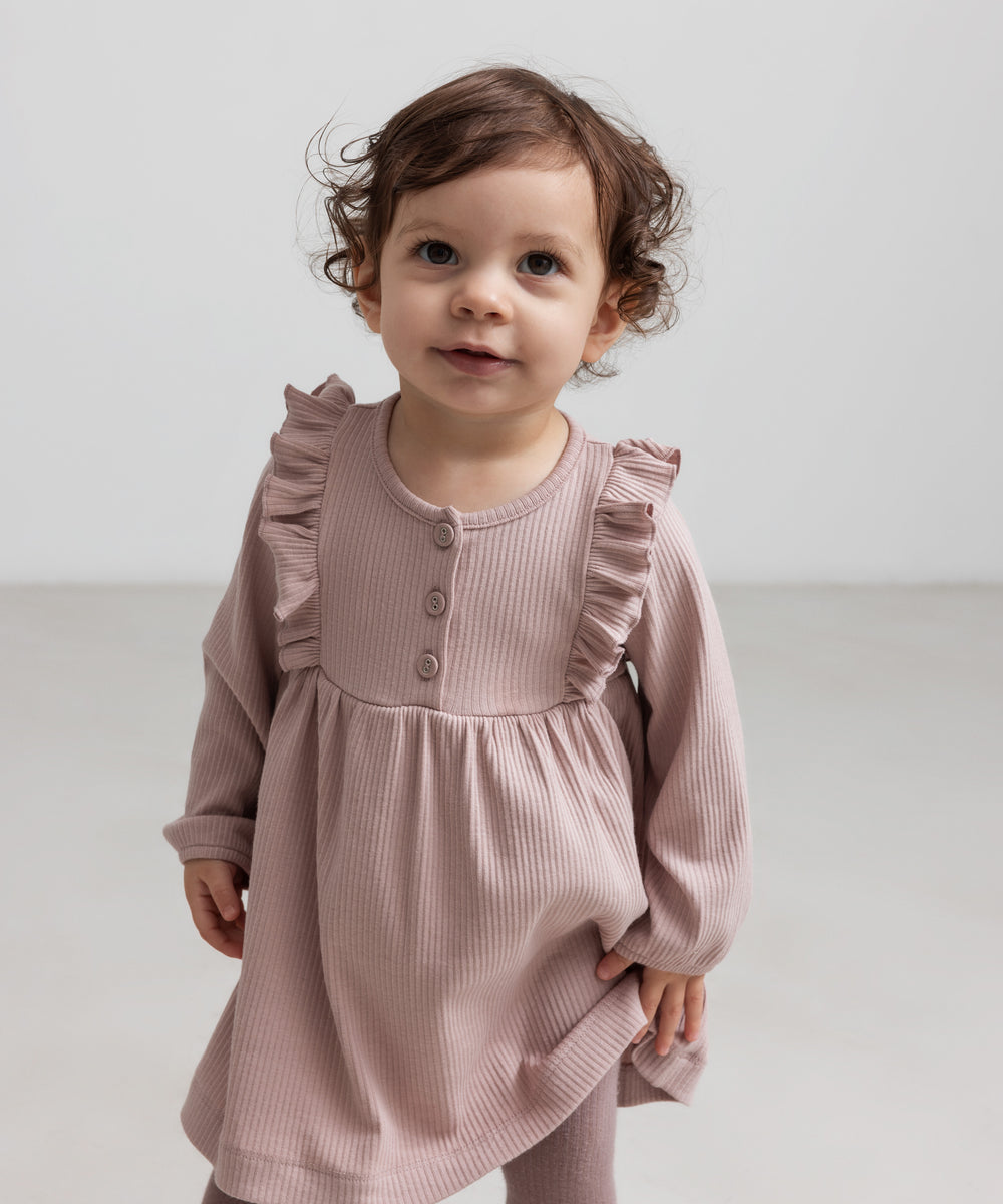 Børn iført lyserød ribstrikket kjole med flæsedetaljer og lange ærmer
