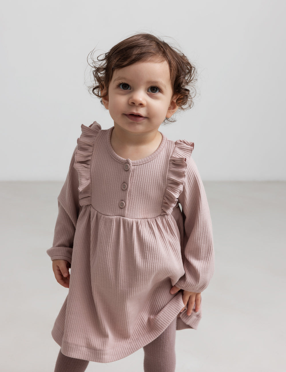 Børn iført lyserød ribstrikket kjole med flæsedetaljer og lange ærmer