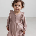 Børn iført lyserød ribstrikket kjole med flæsedetaljer og lange ærmer