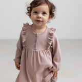 Børn iført lyserød ribstrikket kjole med flæsedetaljer og lange ærmer