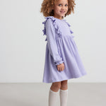 Pige i langærmet lilla ribstrikket kjole med flæser