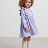 Pige i langærmet lilla ribstrikket kjole med flæser