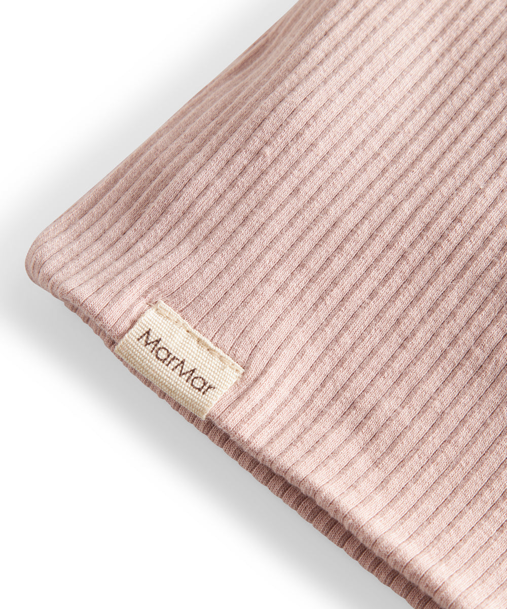 Detalje af ribstrikket lys rosa stof og mærke på børnehue