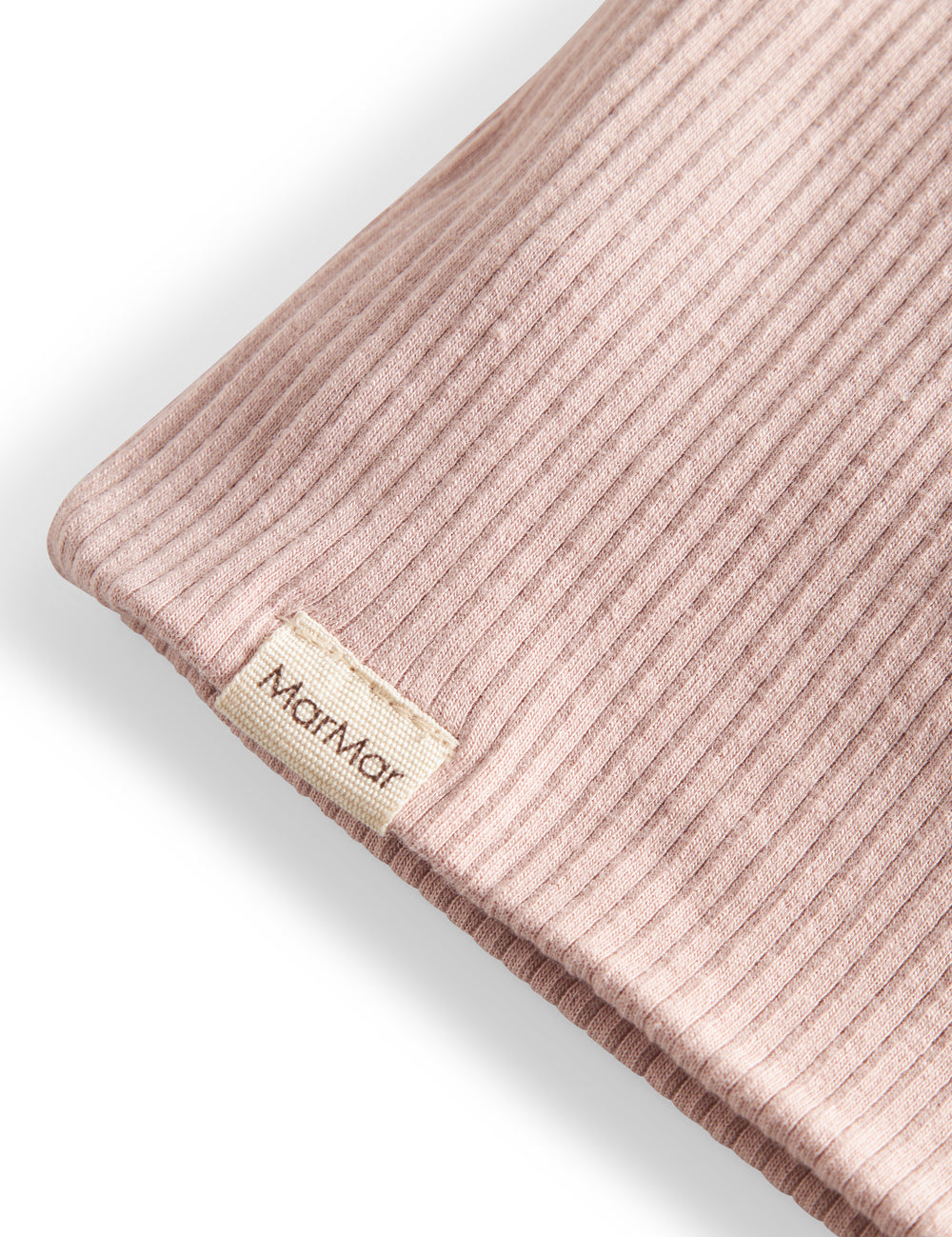 Detaljer af ribstrikket lys rosa stof og mærke på børnehue