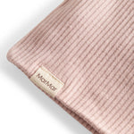 Detalje af ribstrikket lys rosa stof og mærke på børnehue