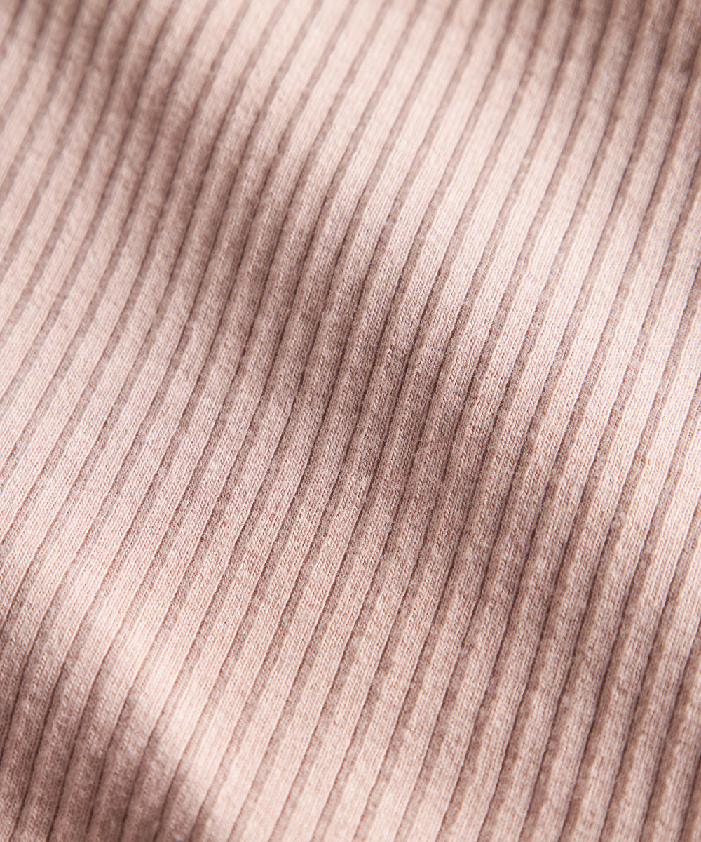 Detalje af lys rosa ribstrikket stof på børnehue