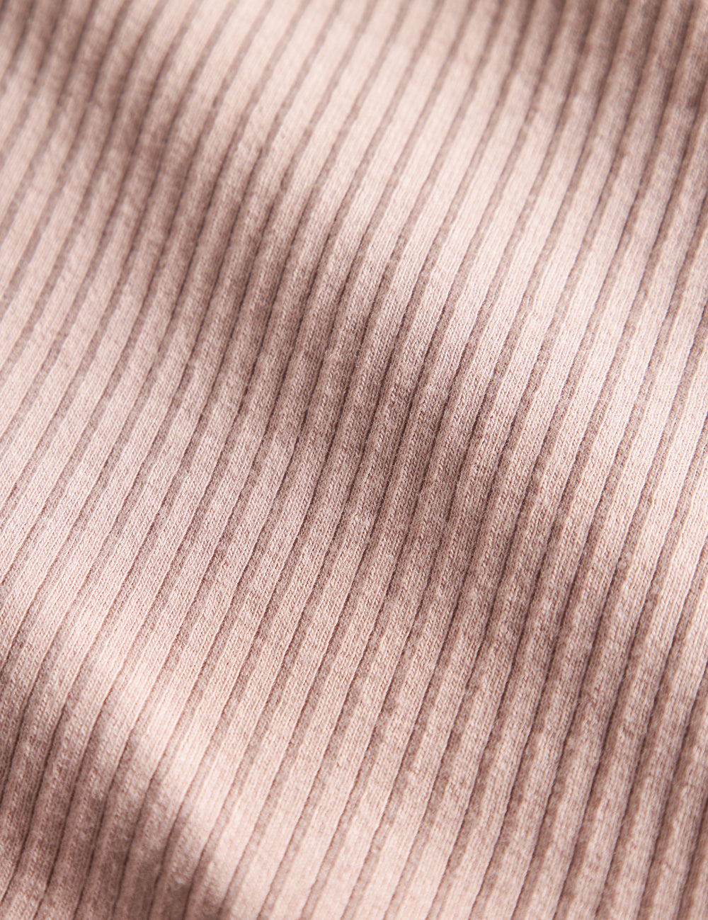 Detalje af lys rosa ribstrikket stof på børnehue