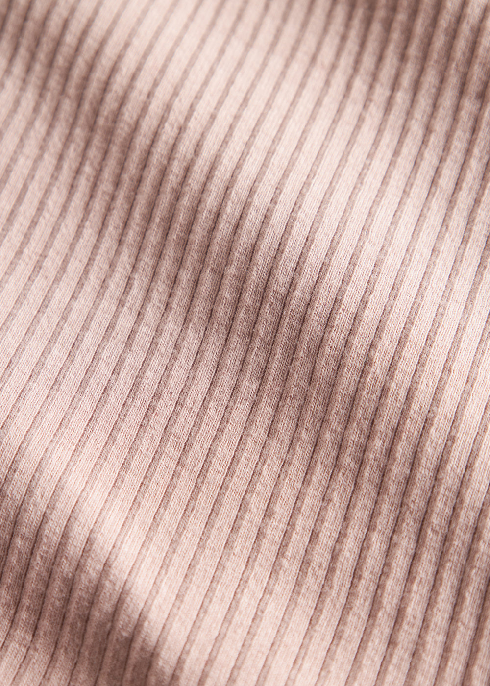 Detalje af lys rosa ribstrikket stof på børnehue