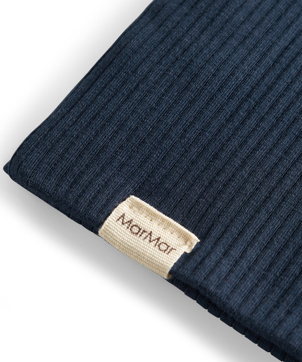 Detalje af ribstrikket navy blå stof og mærke på børnehue