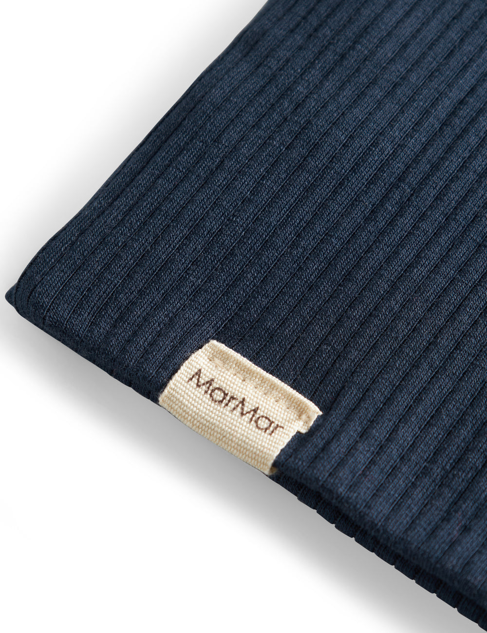 Detaljer af ribstrikket navyblå stof og mærke på børnehue