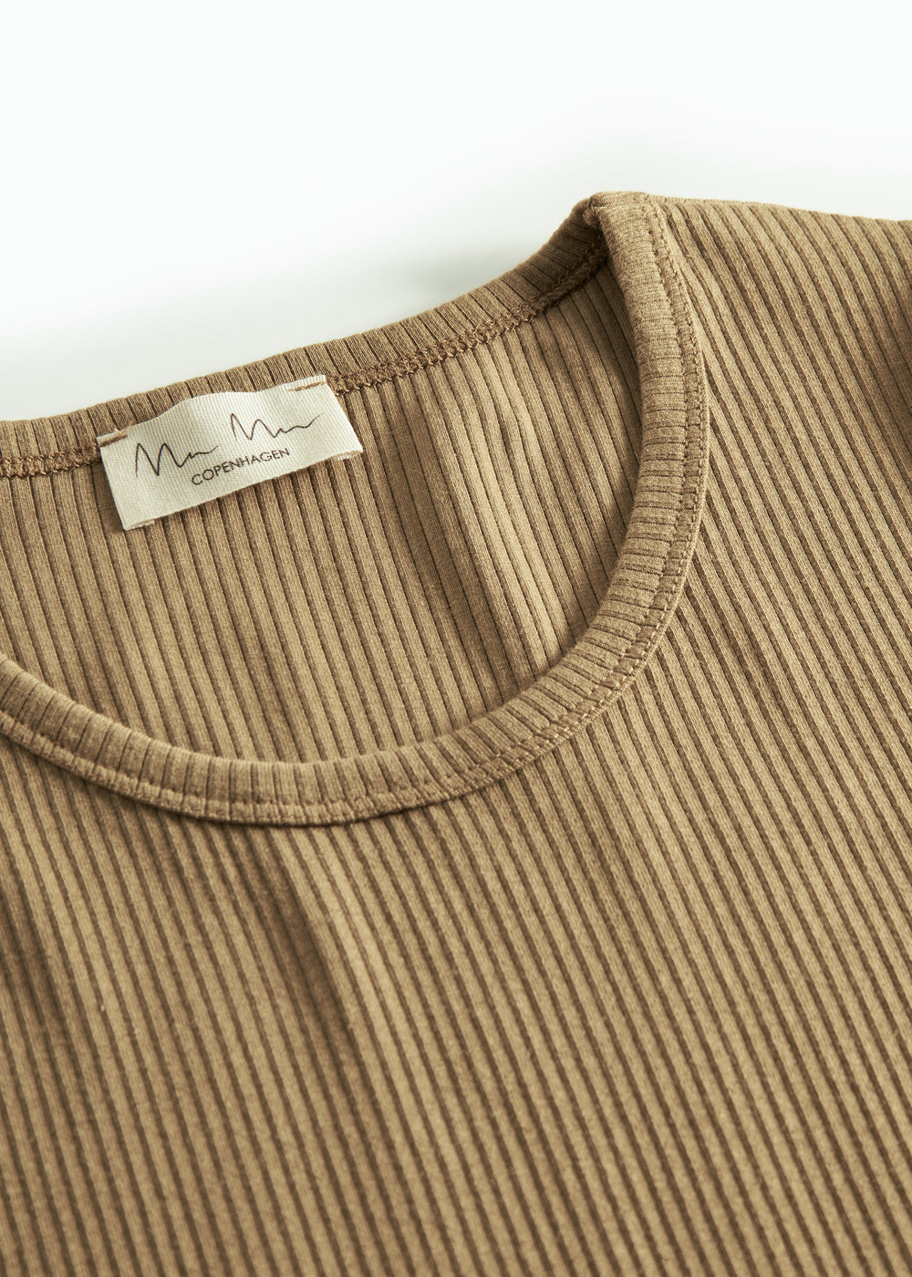Detalje af ribstrikket stof ved halsudskæringen på brun t-shirt