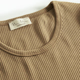 Detalje af ribstrikket stof ved halsudskæringen på brun t-shirt