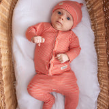 Baby iført rød og hvid stribet hue og heldragt liggende på ryggen