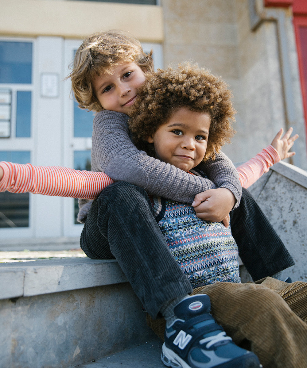 To børn sidder sammen, den ene i mønstret strikvest