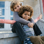 To børn sidder sammen, den ene i mønstret strikvest