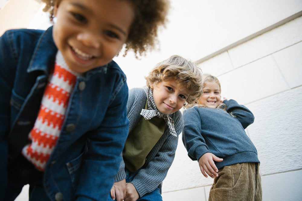 Tre børn iført efterårstøj med strik og denimjakker og tørklæde