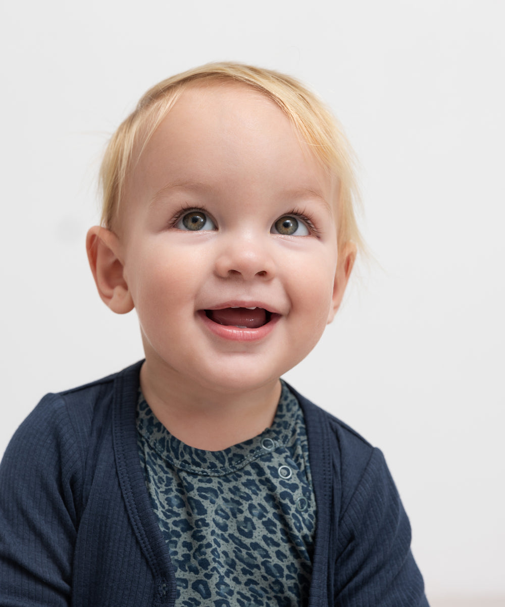 Baby i grøn leopardmønstret babybody med lange ærmer