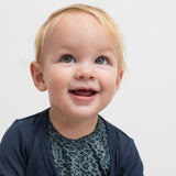 Baby i grøn leopardmønstret babybody med lange ærmer