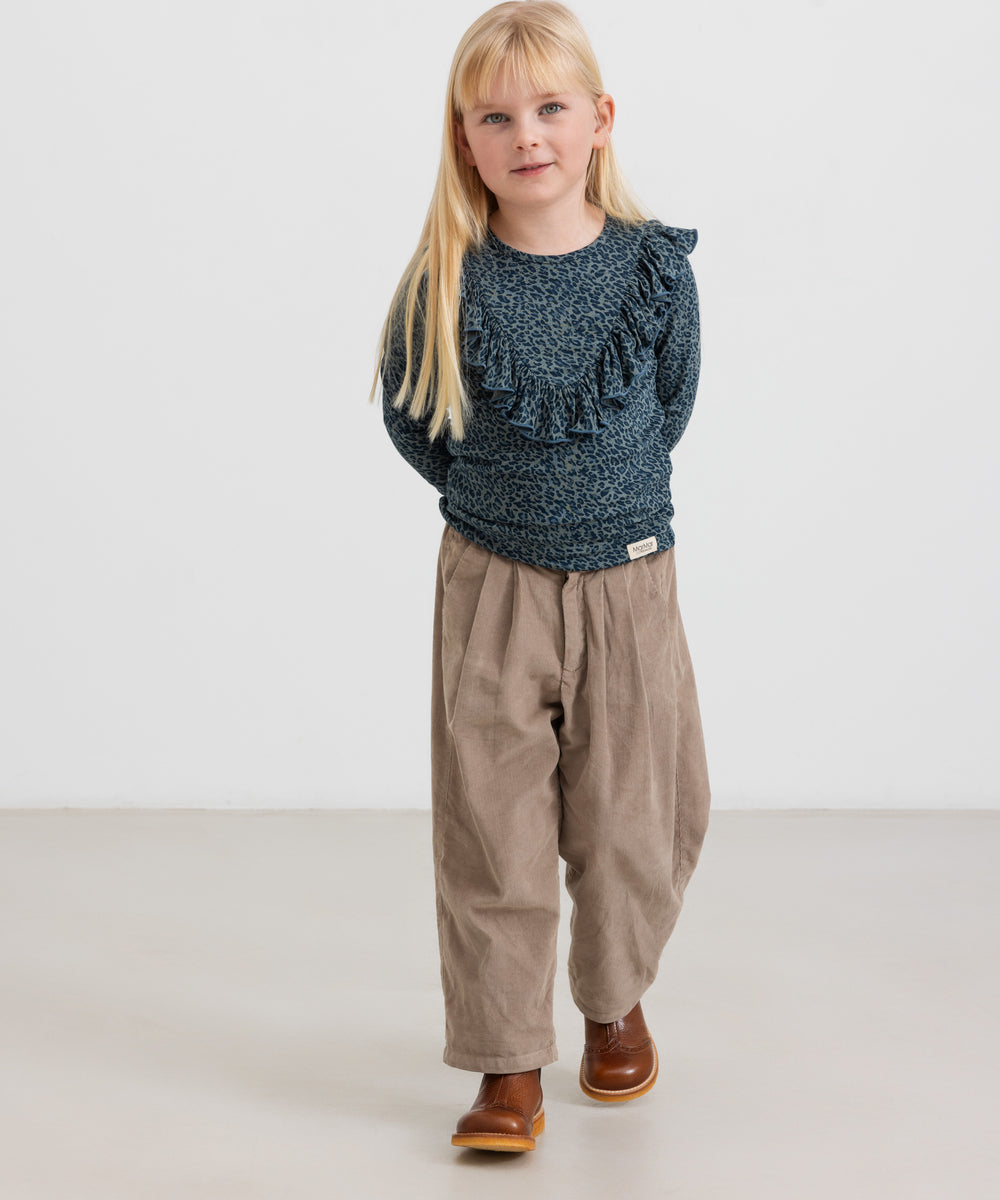 Pige iført beige babyfløjl­sbukser og mørkeblå bluse