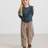 Pige iført beige babyfløjl­sbukser og mørkeblå bluse