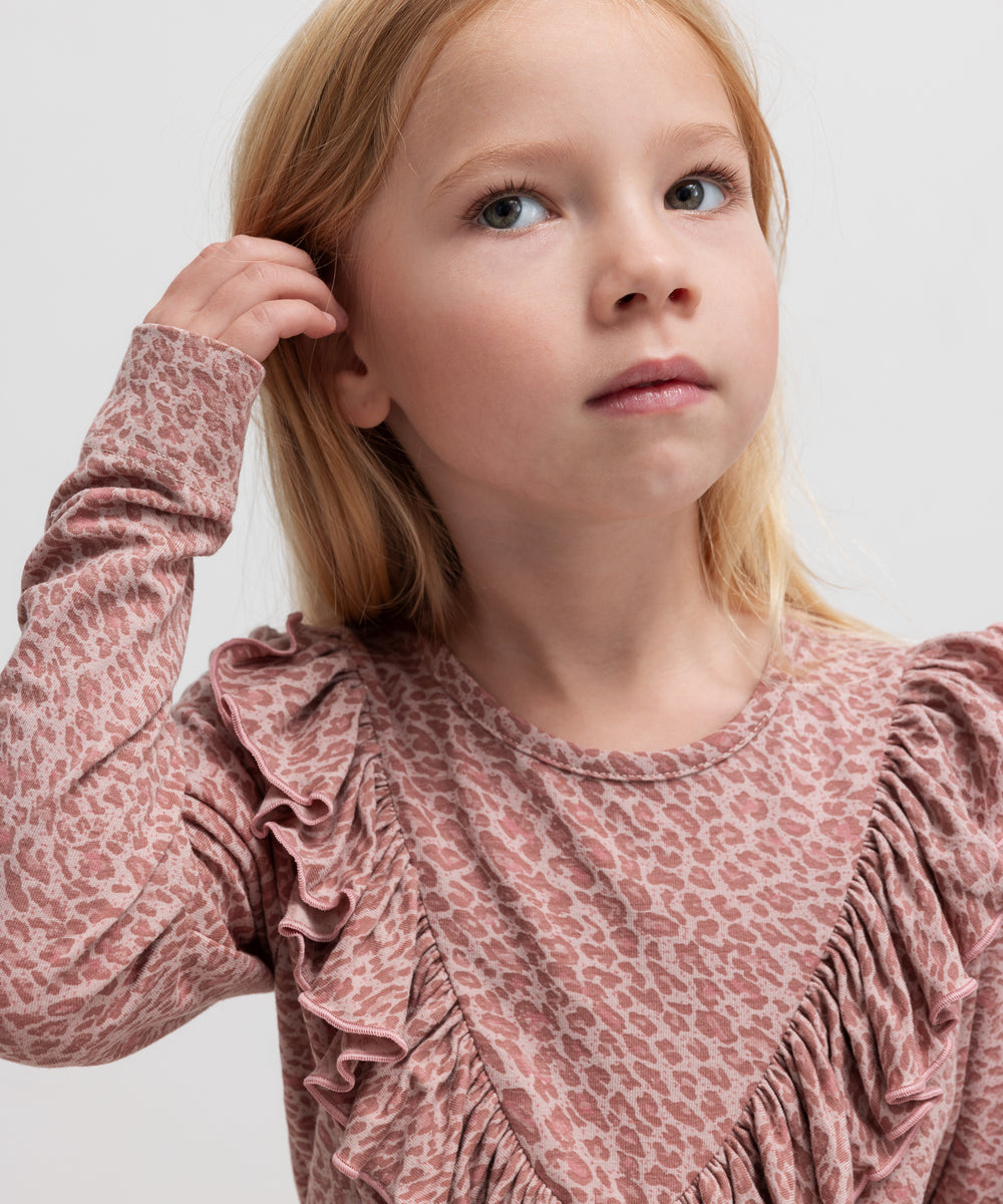 Pige iført lyserød leopardmønstret bluse med flæsedetalje