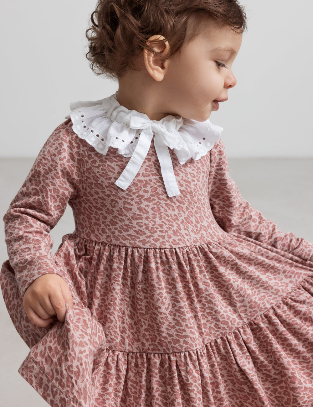 Pige iført lyserød leopardmønstret kjole med hvid krave