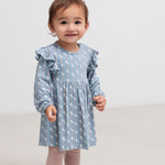 Baby iført blå kjole-body med enhjørningemønster