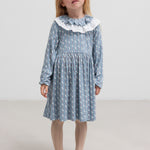 Pige iført blå kjole med enhjørningemønster og flæsekrave