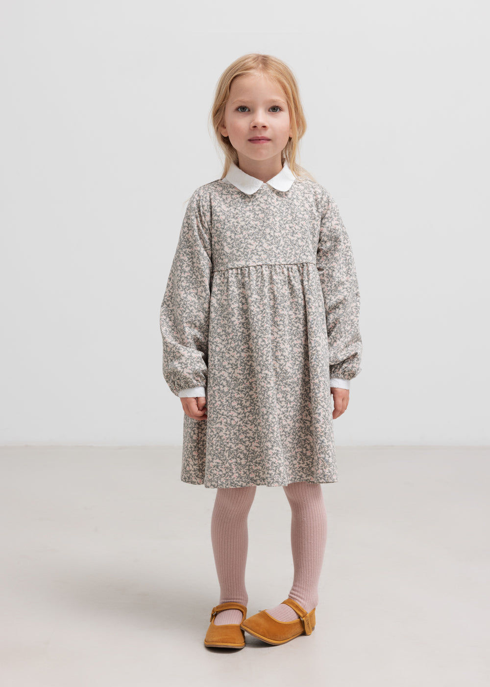 Børn iført lys kjole står mod en hvid baggrund