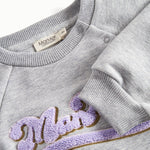 Nærbillede af broderi og ribkant på grå sweatshirt til børn