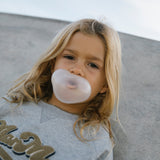 Børn med grå sweatshirt, der puster boble med tyggegummi