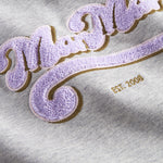 Nærbillede af lila broderet logo på grå sweatshirt til børn