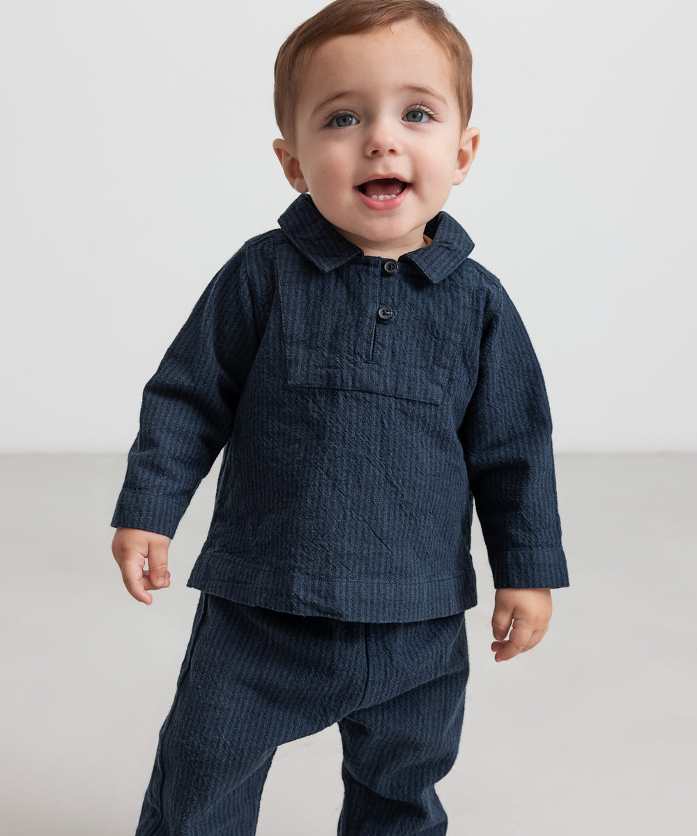 Lille barn iført mørkeblå bukser og matchende skjorte